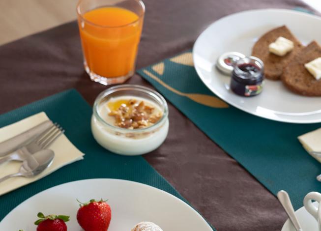 Colazione con croissant, fragole, yogurt e succo d'arancia.