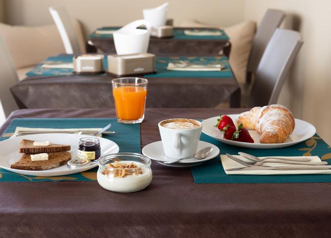 Colazione con cappuccino, croissant, fragole e succo d'arancia.