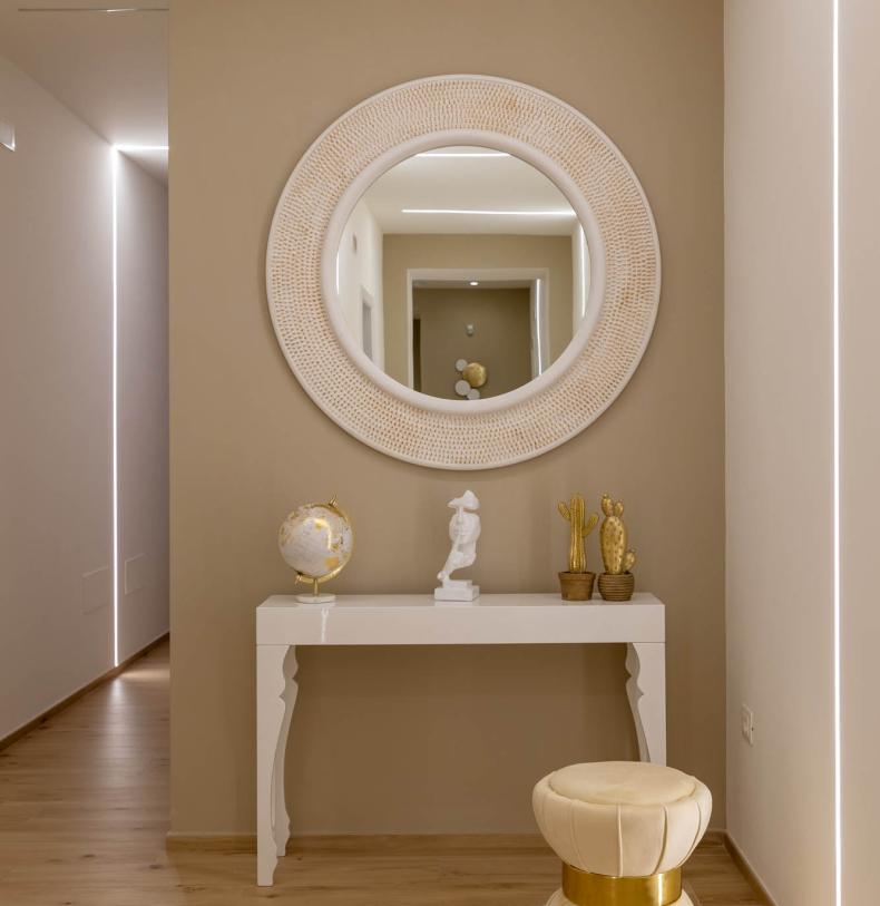 Elegant entryway with round mirror and golden decorations.