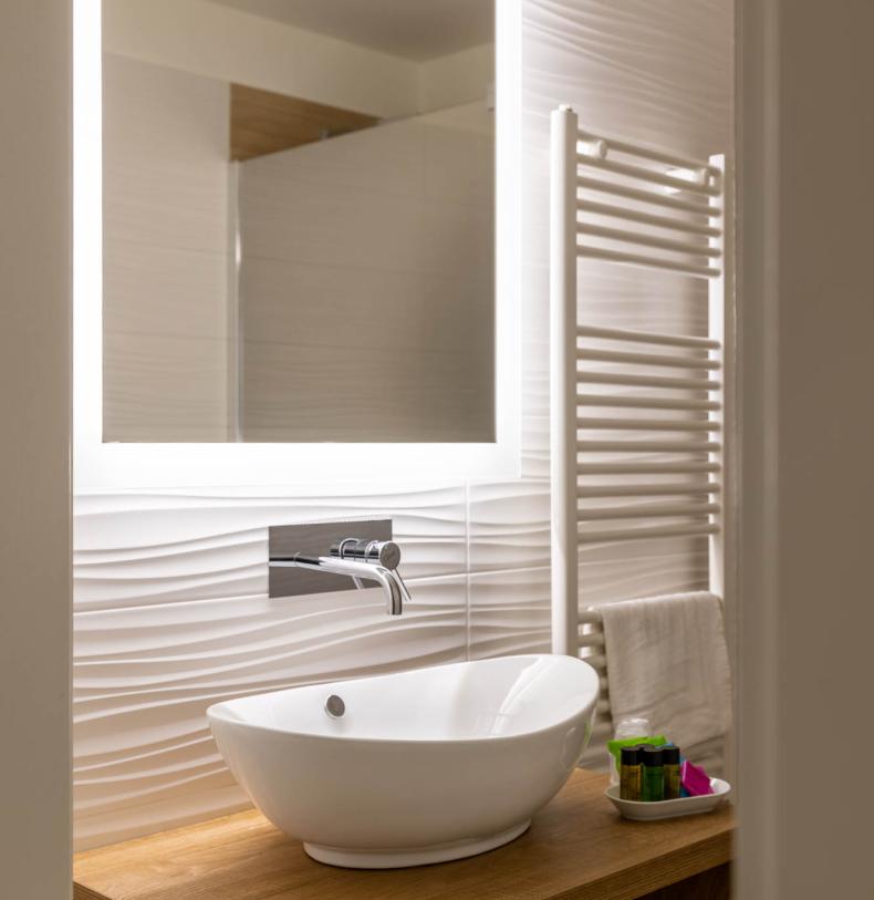 Elegante bagno con lavabo moderno e specchio illuminato.