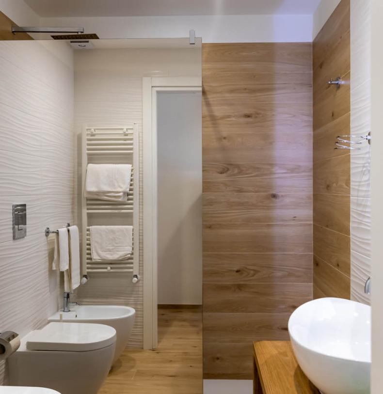 Bagno moderno con legno e ceramica, lavabo bianco e doccia.