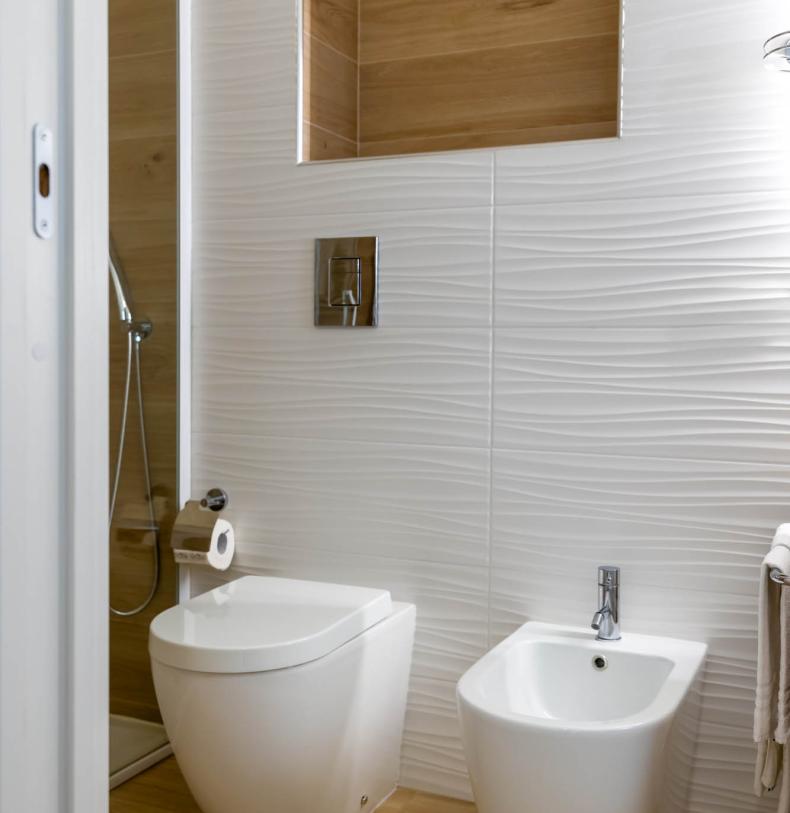 Bagno moderno con bidet e WC su pavimento in legno.